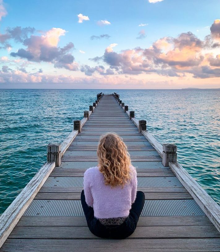 femme assise pont mer coucher soleil