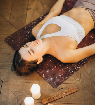Femme allongée sur le sol avec bougis Yoga Nidra